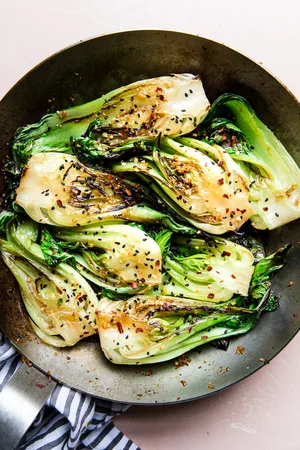 stir fried bok choy with garlic soy sauce and sesame seeds in a skillet