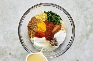 yogurt, lemon juice, ginger, garlic, turmeric, chili powder, cayenne, cinnamon, cumin, cilantro, salt & pepper in a bowl