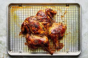 a whole roasted tandoori chicken on a metal rack lined baking sheet