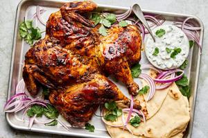A whole roasted tandoori chicken served with warm pita bread and a side of creamy raita for dipping.