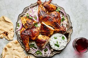 A whole roasted tandoori chicken served with warm pita bread and a side of creamy raita for dipping.