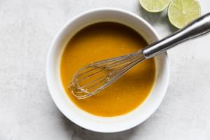 White bowl filled with Thai Salad Dressing ingredients mixed with a wire whisk