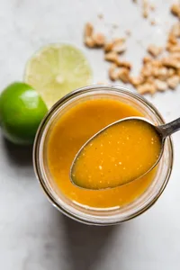 spoon in a glass jar with thai salad dressing