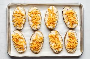 baked potatoes filled with potato and cheese mixture topped with cheddar cheese