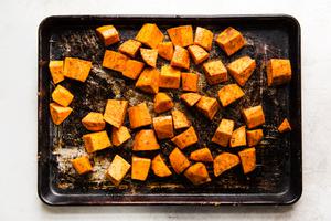 sheet pan of cubed raw sweet potatoes seasoned