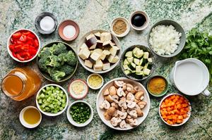 ingredients for vegetable curry soup in bowls: onion, celery, carrots, mushrooms, eggplant, broccoli, bell pepper & zucchini