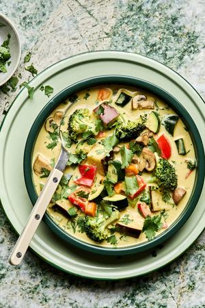 a bowl of vegetable curry soup made with onion, celery, carrots, mushrooms, eggplant, broccoli, bell pepper and zucchini