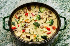 all ingredients for vegetable curry soup cooking in a pot including broccoli, eggplant, zucchini and bell pepper