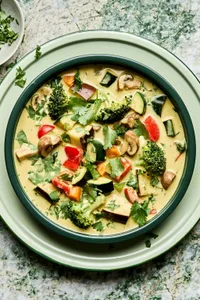 a bowl of vegetable curry soup made with onion, celery, carrots, mushrooms, eggplant, broccoli, bell pepper and zucchini