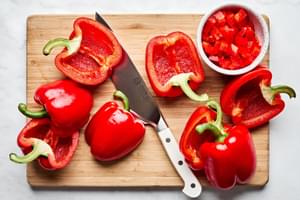 bell peppers being prepped to make stuffed peppers by cutting them in half and deseeding them