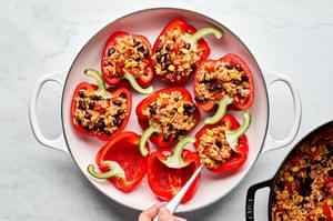 halved bell peppers being filled with a bean and rice filling