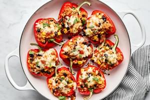 Vegetarian stuffed bell peppers in a casserole dish, topped with melted pepper jack cheese and garnished with cilantro