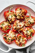 Vegetarian stuffed bell peppers in a casserole dish, topped with melted pepper jack cheese and garnished with cilantro