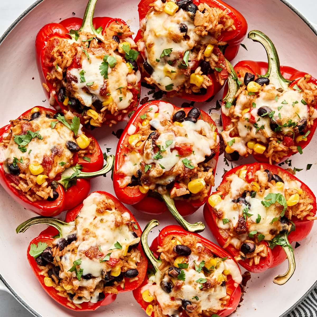 Vegetarian stuffed bell peppers in a casserole dish, topped with melted pepper jack cheese and garnished with cilantro