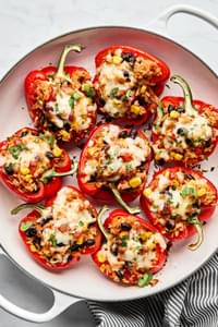 Vegetarian stuffed bell peppers in a casserole dish, topped with melted pepper jack cheese and garnished with cilantro
