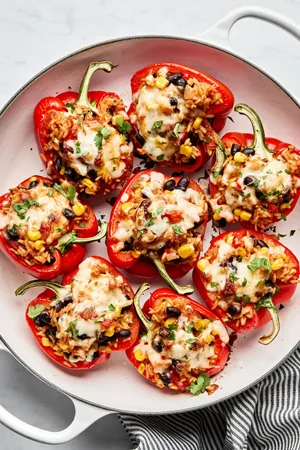 Vegetarian stuffed bell peppers in a casserole dish, topped with melted pepper jack cheese and garnished with cilantro
