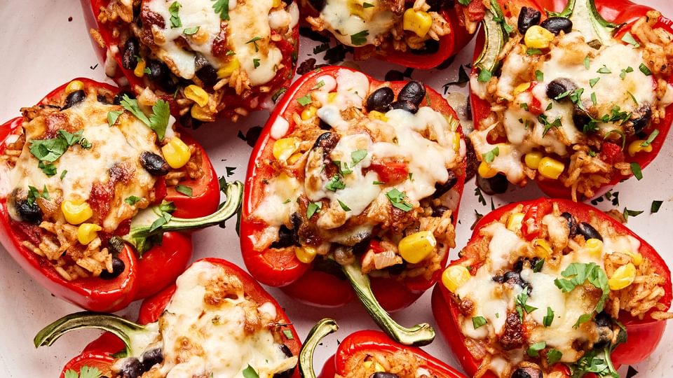 Vegetarian stuffed bell peppers in a casserole dish, topped with melted pepper jack cheese and garnished with cilantro