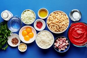 ingredients for vodka sauce carbonara in prep bowls: pasta, crushed tomatoes, garlic, pancetta, parmesan, cream and vodka