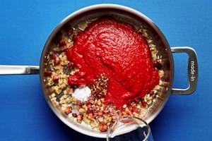 onion, pancetta, garlic, tomatoes, tomato paste, red pepper flakes salt and vodka being poured into a large sauce pan