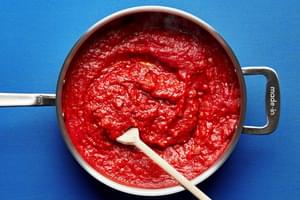onion, pancetta, garlic, tomatoes, tomato paste, red pepper flakes salt and vodka being stirred in a large sauce pan