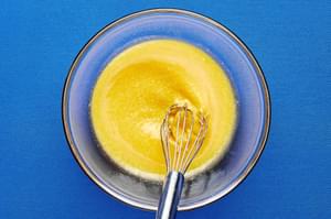 eggs, parmesan cheese, and reserved pasta water being whisked together in a glass bowl