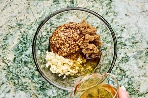 whole-grain mustard, olive oil, apple cider vinegar, brown sugar, and minced garlic being combined in a bowl