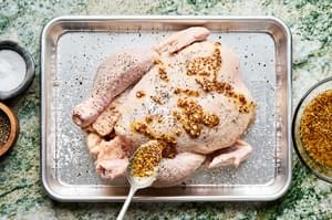 whole-grain mustard, olive oil, apple cider vinegar, brown sugar, and minced garlic being brushed on a whole chicken