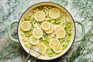 leeks, lemon slices, olive oil and wine layered on the bottom of a pan