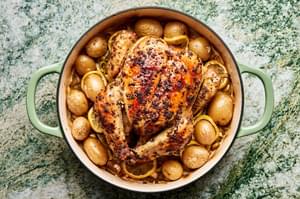 A whole roast chicken paired with crispy potatoes and tender leeks, golden and perfectly roasted for a comforting meal.