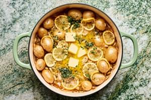 tarragon and butter being stirred into a pot with cooked potatoes, leeks and lemon slices