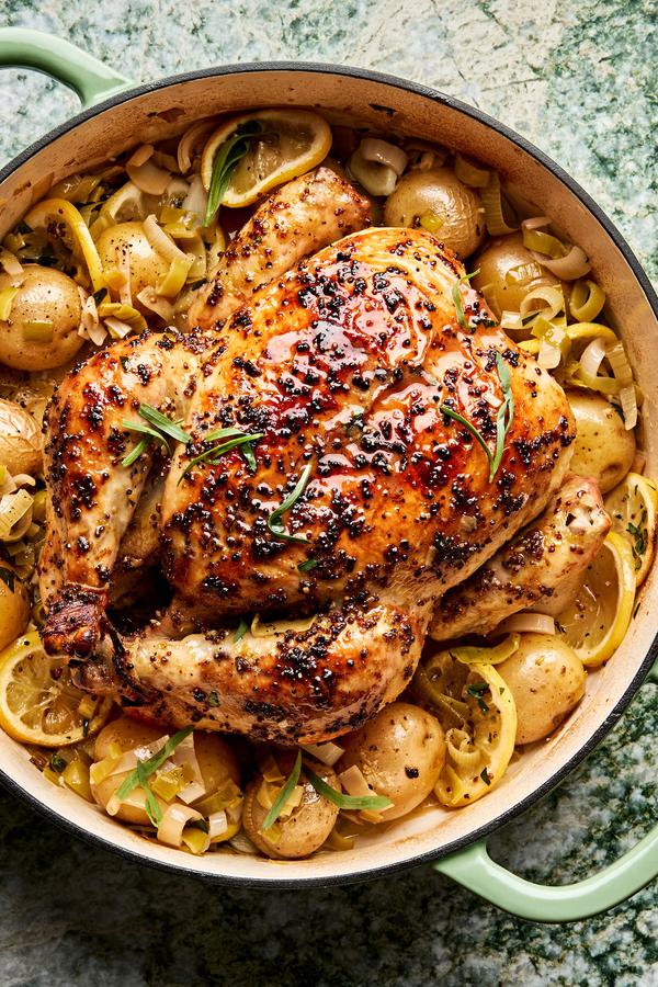 A whole roast chicken paired with crispy potatoes and tender leeks, golden and perfectly roasted for a comforting meal.