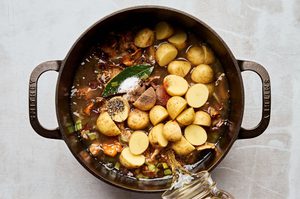 wild mushroom chowder with potatoes, bacon and leeks being cooked in a pot to make a cozy fall meal