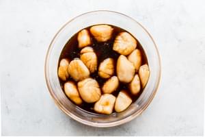 large sea scallops marinating in a glass bowl