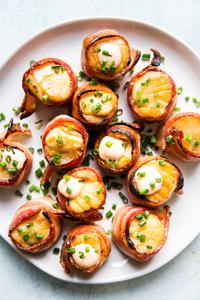 bacon wrapped sea scallops on a plate topped with fresh chives
