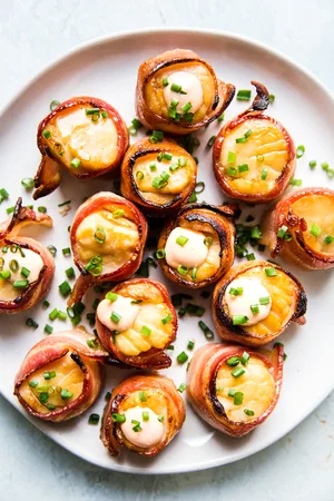 bacon wrapped sea scallops on a plate topped with fresh chives