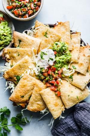 platter of baked chicken quesadillas with fresh pico de gallo, guacamole and sour cream
