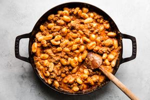 raw gnocchi mixed with ricotta, sausage, marinara and spices in a black skillet