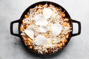 gnocchi mixed with marinara and tomato sauce in a black skillet topped with grated mozzarella cheese