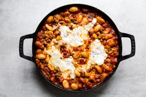 baked gnocchi with tomato sauce and sausage in a black skillet topped with melted mozzarella cheese