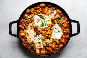 baked gnocchi with tomato sauce and sausage in a black skillet topped with melted mozzarella cheese