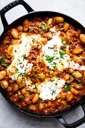 baked gnocchi with tomato sauce and sausage in a black skillet topped with melted mozzarella cheese