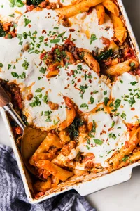 Baked Penne Alla Vodka with kale and mozzarella in a pan with a serving spoon