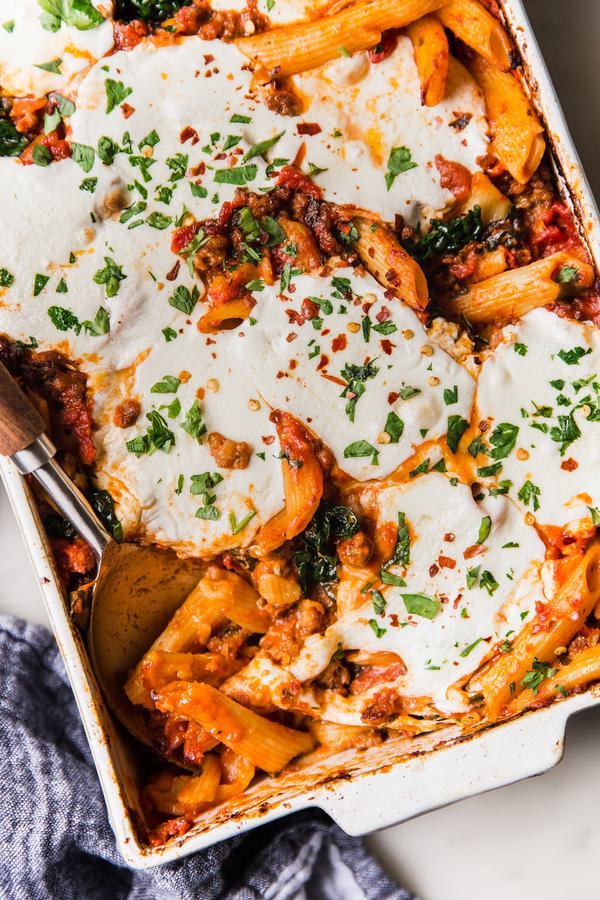 Baked Penne Alla Vodka with kale and mozzarella in a pan with a serving spoon