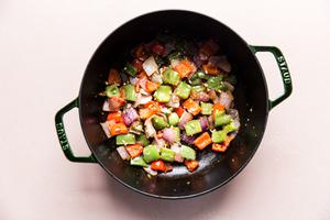 Onion and bell peppers being cooked in olive oil in a large soup pot
