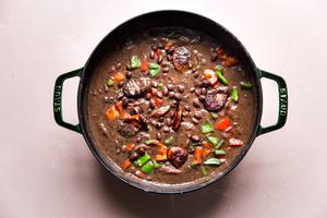 a pot of homemade Black Bean Soup With Smoked Sausage, onion and bell peppers in a pot