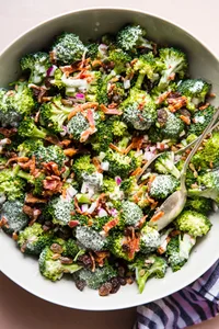 A bowl of fresh broccoli salad with creamy sweet dressing, crispy bacon, golden raisins and purple onions