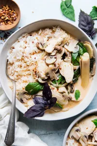 Coconut Chicken Soup Tom Kha Gai in a bowl with basil and rice and a spoon