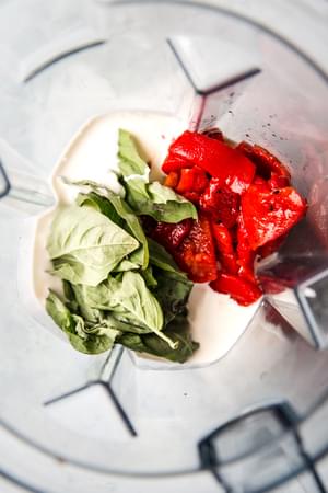 blender filled with heavy cream, roasted red peppers and fresh basil