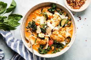 Creamy Tomato And Mixed Vegetable Soup With Italian Chicken Sausage in a bowl with a spoon