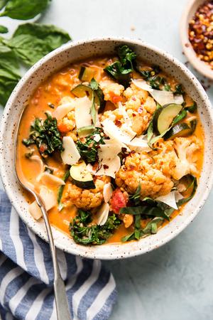 Creamy Tomato And Mixed Vegetable Soup With Italian Chicken Sausage in a bowl with a spoon